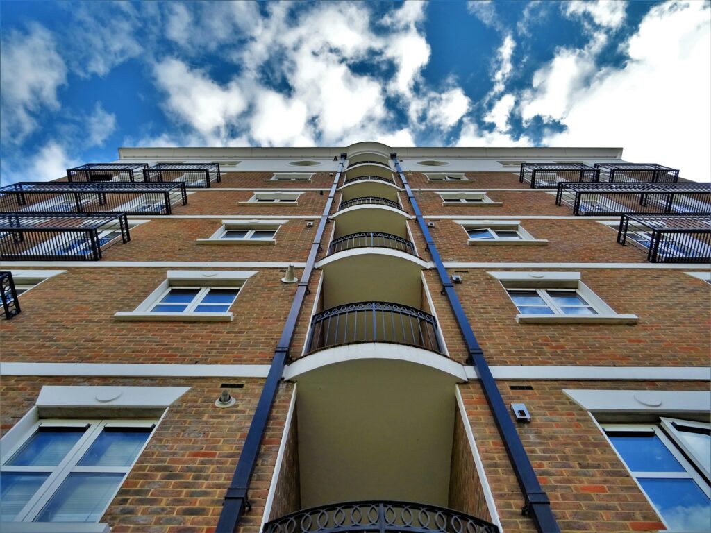 Low angle view of a modern urban apartment building with balconies under a clear blue sky.