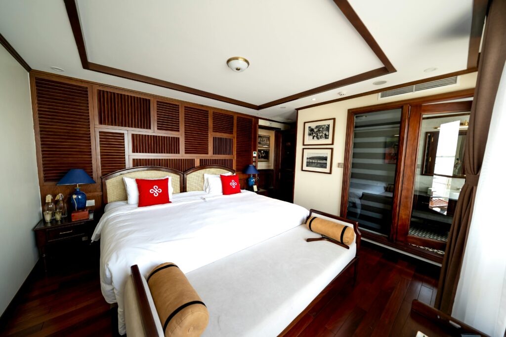 A luxurious hotel room featuring elegant wooden decor and a comfortable double bed with red accents.